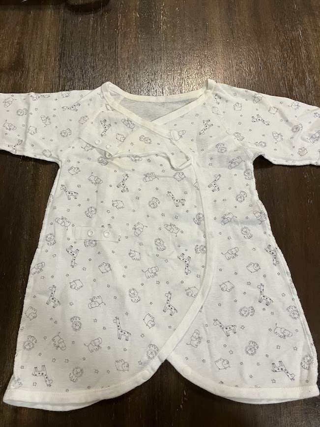 新生児のベビー肌着をはじめ子供の服はどれも小さく、大人の服と同じたたみ方をすると崩れやすいなと感じているのではないでしょうか？

そのような時は袖を入れ込み①長方形を作る方法と②くるくる丸める方法が崩れないのでおすすめです。

服のデザインや服の生地によってどちらが適しているかは変わってきますが、たたみ方はこのどちらかの方法でほぼ対応できます。

またたたみ終わりが自立した状態にできると収納するときに便利ですよ。それでは詳しく見ていきましょう。

ベビー肌着のたたみ方

私はベビー肌着のたたみ方は前開きかかぶりかで変えていました。

ベビー肌着には、主に以下の4つの種類があります。

ベビー肌着の種類

短肌着

長下着

コンビ肌着

ロンパース肌着(前開き・かぶり）

①～③や④の前開きの肌着は、主に生まれてから3～6カ月の首が座り足の動きが活発になる頃まで、夏ならどれか１枚、冬なら①+②や①+③で組み合わせて使うことが多いでしょう。

お座りが安定したころになると、かぶりの肌着が着せやすくなりますよ。

前開きのベビー肌着

前開きを着ている時期はあまり外に遠出することも少なかったので、たたみ方はただただコンパクトに折りたたんでいました。

写真は③コンビ肌着ですが、①や②も同じたたみ方をしていました。

1⃣広げて手でシワを伸ばす

2⃣半分におり、袖を折りたたみ長方形を作る

3⃣首の方から下にくるくる巻く

4⃣完成

 自立します

このたたみ方は、片づけ収納アドバイサーの近藤麻理恵さん（通称こんまりさん）を参考にしていました。

また冬は①短肌着と一緒に着るので、たたむ時に2枚重ねてたたむと着せるときに便利でしたよ。

前開きの肌着でも、夏場に活躍する生地が非常に薄いメッシュ素材のものは丸めて収納していました。

1⃣広げて手でシワを伸ばす

2⃣真ん中で３等分にし、長方形を作る

3⃣首元からくるくる巻く

4⃣完成

 自立します

生地が薄い時はなかなか自立してくれませんが、くるくる巻くことでしっかり自立させることができます。

使うときにめんどくさいので、ボタンは留めずにそのまま折りたたんでも問題なく崩れないで収納できました。

かぶりのベビー肌着（ロンパース）

かぶりの肌着が着れるころになると少しずつ外出することも増えてきたので、カバンの中でたたんだものが崩れないように、裾を首元に入れこむたたみ方をしていました。

1⃣広げてシワを伸ばす

2⃣真ん中に3等分にたたみ、袖を折込み長方形を作る

3⃣首周りを１回、下から2・3回折る

4⃣首元のわっかの中に下から折ってきた分を入れ込む

5⃣完成

わっかに入れ込むことで、少々放り投げても崩れてしまうことはありません。

2⃣の状態からくるくる巻き下のボタンで留める方法もありますが、私にはこの方法があっていました。

前開きもかぶりタイプも袖を中に折り曲げて縦長の長方形をつくり、たたみ終わりがつるんとした四角い状態で自立していることが理想です。

慣れるまではめんどくさく感じるかもしれませんが、ベビー服に限らず子供服や大人の服に応用出来て便利ですよ。

おむつ替えセット

日中まだまだ寝ていることの多いころには、おむつやおしりふき、使用済みおむつを入れる袋、着替えやボディケア用品をひとまとめにした、おむつ替えセットを作ると便利ですよ。

ベビーベッドで寝ていたらベッド下に、わが家は日中はリビングで夜は寝室で過ごしていたので、それぞれにカラーボックスサイズの入れ物を置きまとめていました。

ベッド上でおむつを替えることが多い時は、ワゴンタイプのものにひとまとめにしておくのもよいでしょう。

ただ、少しずつ子どもの動きが活発になってくると、とにかく下に物が置けなくなります。

そのようになってきたらタンスや引き出しでの収納を取り入れましょう。

\必要なものをひとまとめにできる!キャスター付きで移動も楽々/